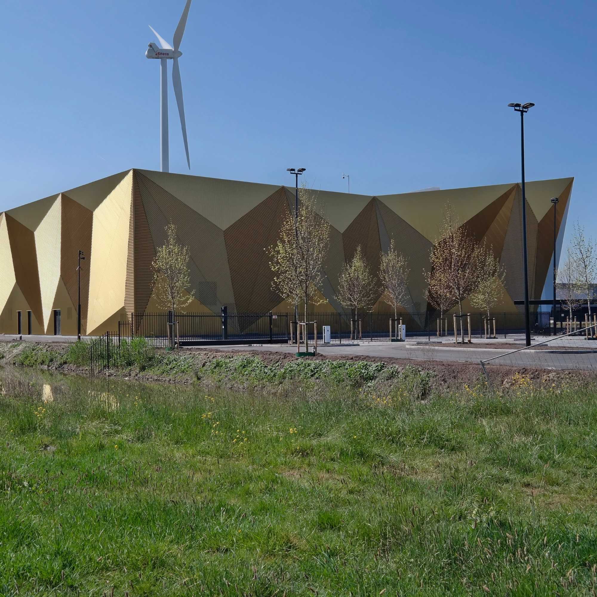 Royal Dutch Mint, modern building with geometric design and a wind turbine against a clear blue sky