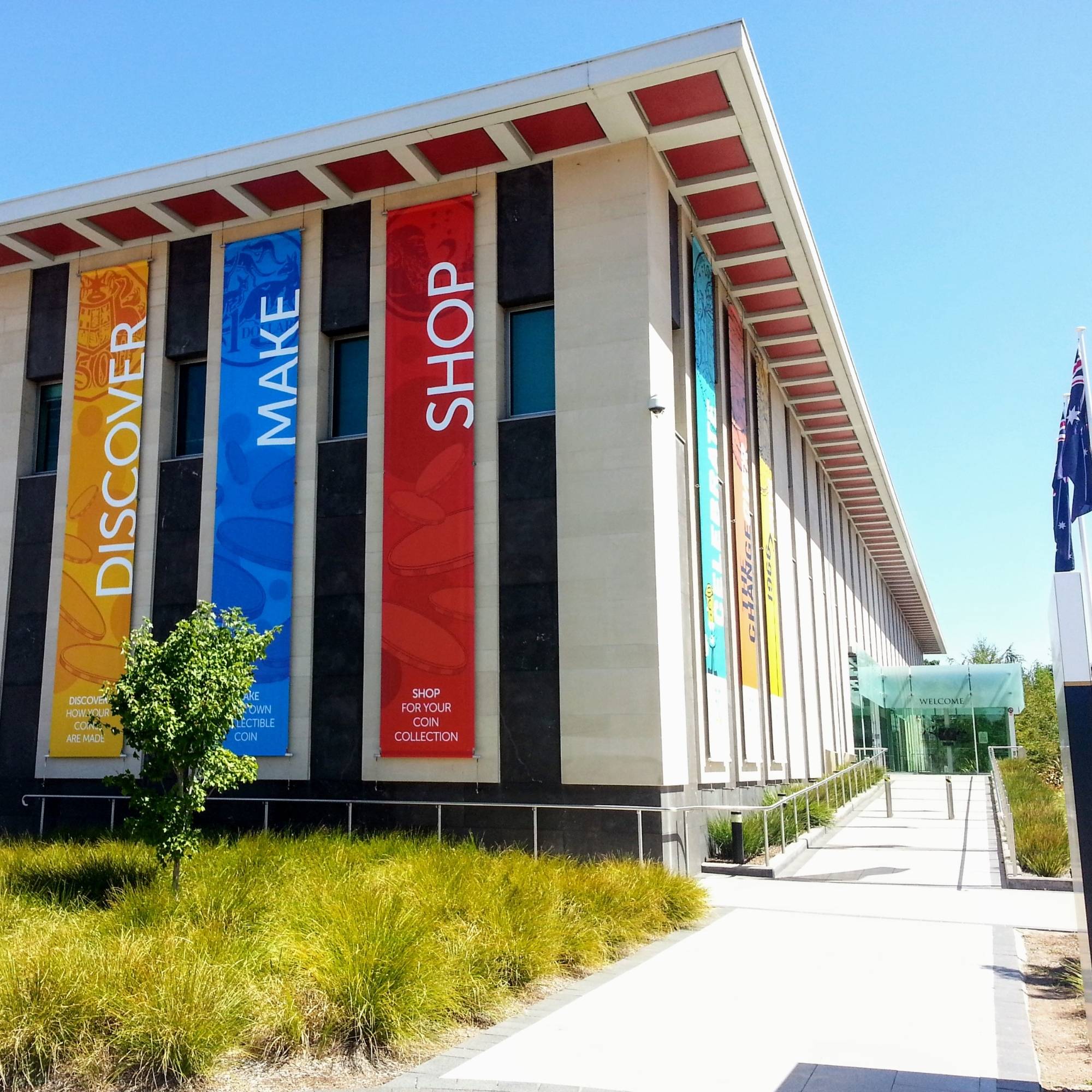 Royal Australian Mint, modern building with colourful banners and a clear blue sky