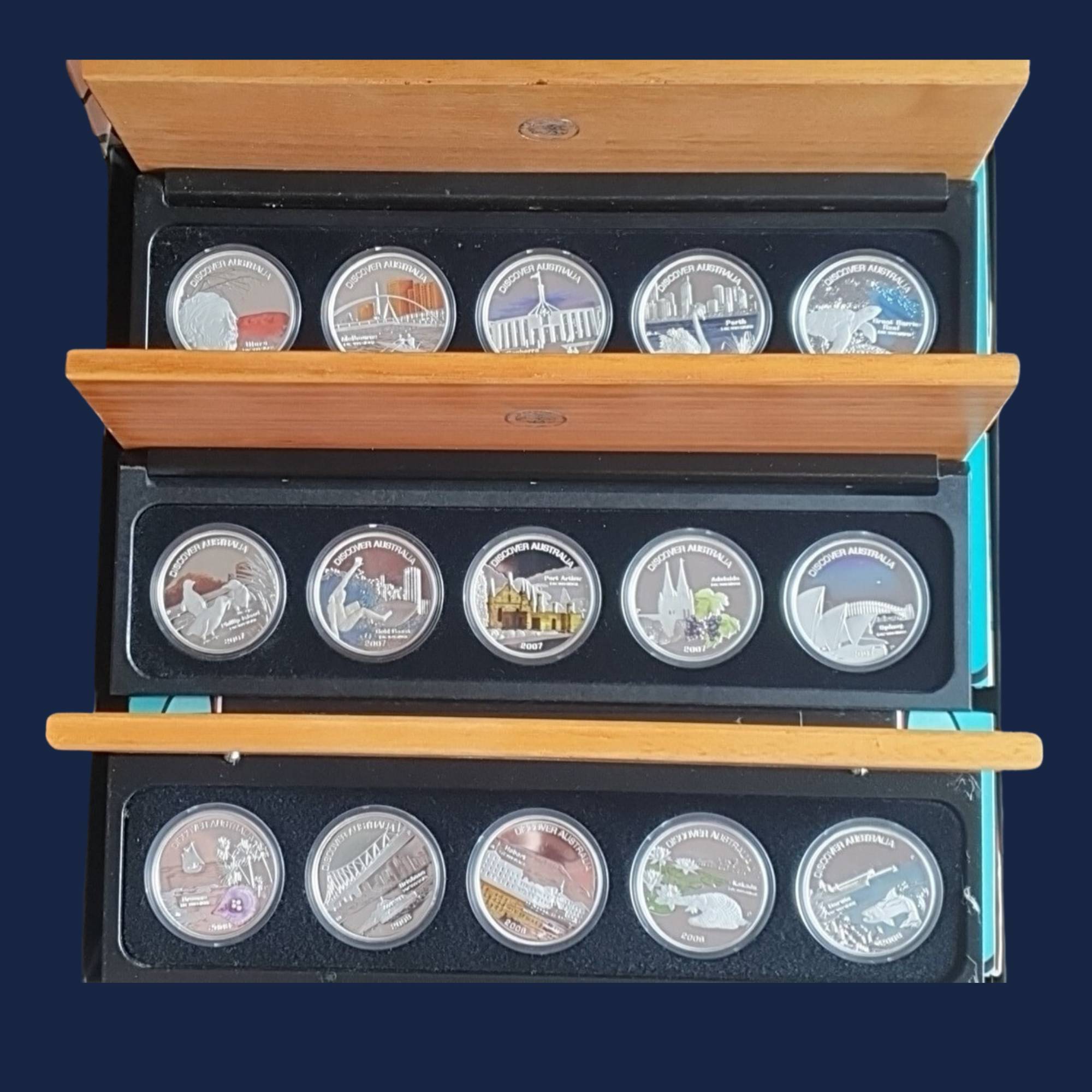 Sets of three times five silver coins from the Perth Mint Discover Australia 2006-2008 series with Australian landmarks in a black case with wooden lid.
